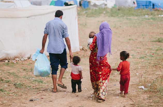 Middle eastern family walks through refugee camp