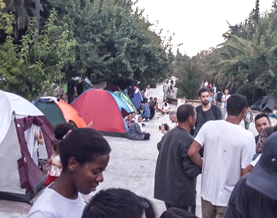 Middle Eastern refugees in tents on a walkway in Greece