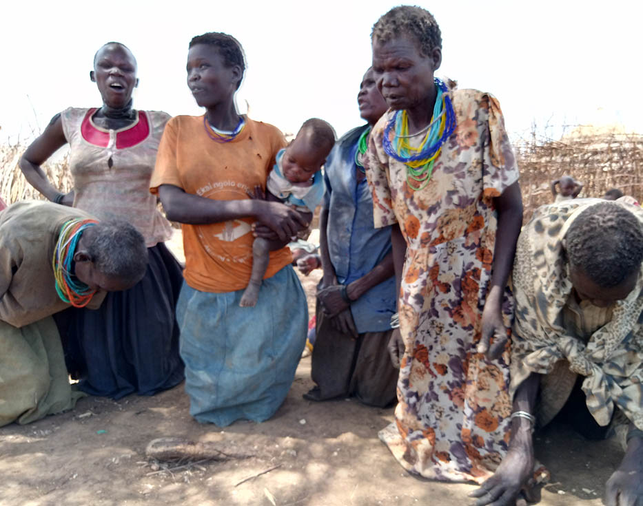 Ugandan women kneel on dirty ground praying