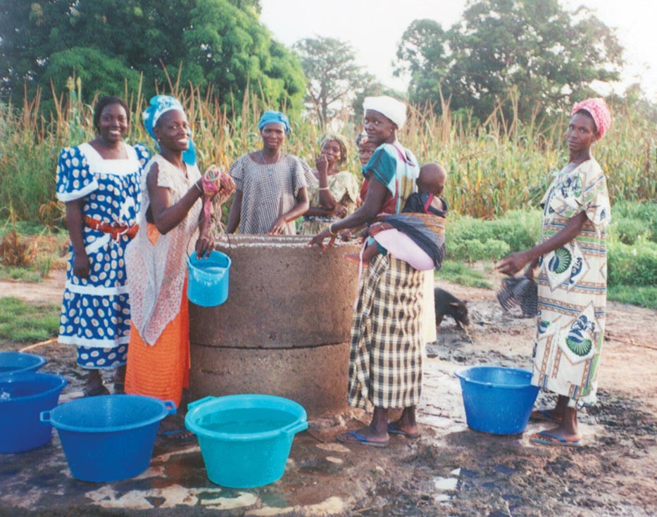 Gambian women take water from a well and put it in buckets