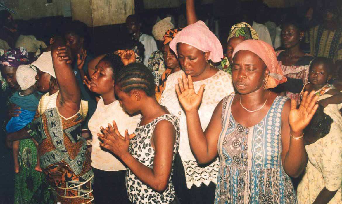 African Christian women praising God with their eyes closed and hands raised