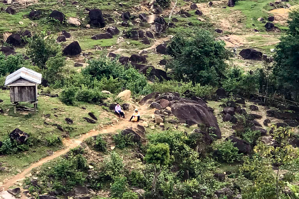 Two men sit on a path on a hillside in Vietnam