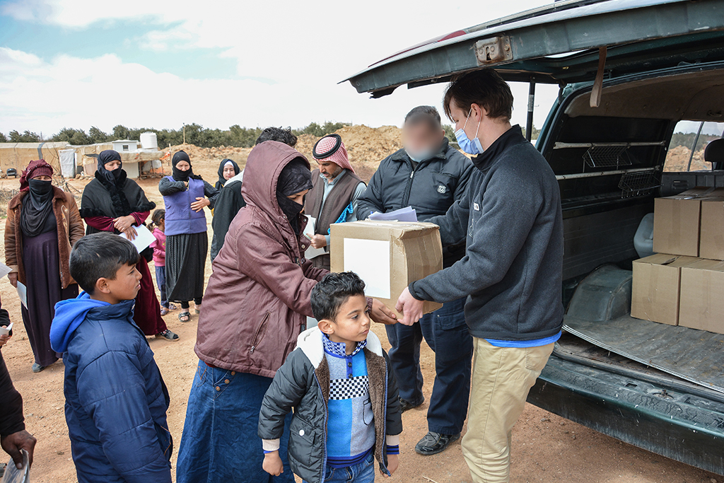 Jordanian woman receives a cardboard box out of the back of an SUV from a Christian missionary