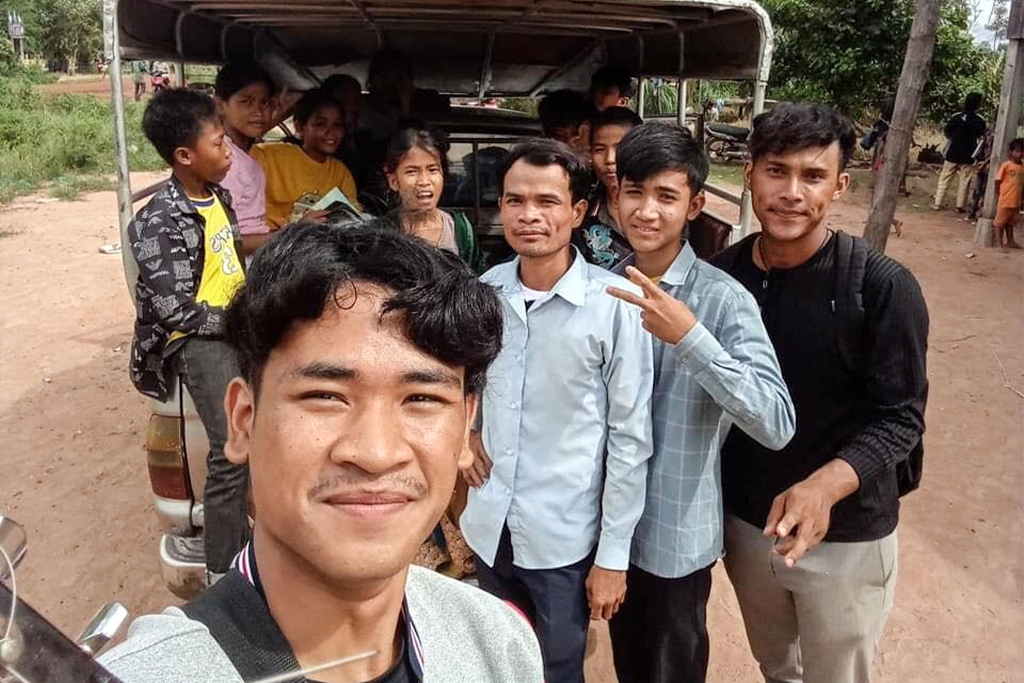 Young Cambodian men and teenagers standing behind a pickup truck with a canopy over the bed