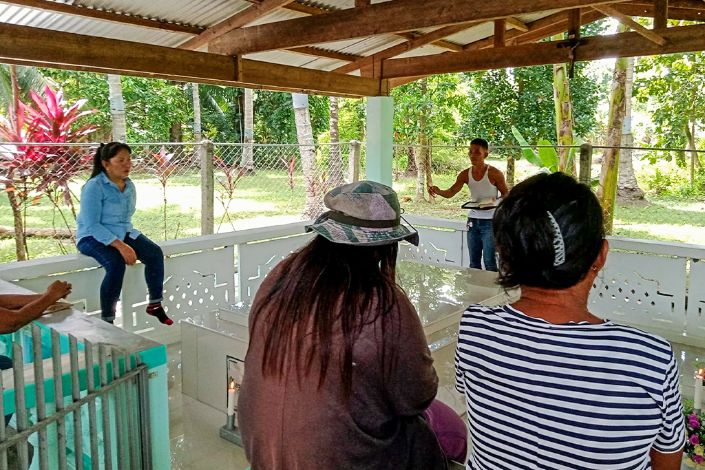 Filipino man holding a bible preaching at a memorial service for a person who passed away
