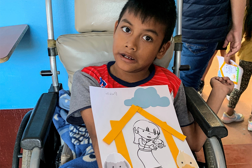 Disabled Guatemalan boy in a wheel chair holding a picture that he made