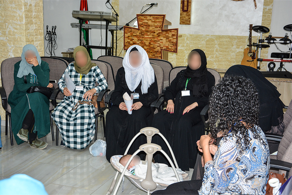 Women wearing head coverings sitting in chairs in a Middle Eastern church
