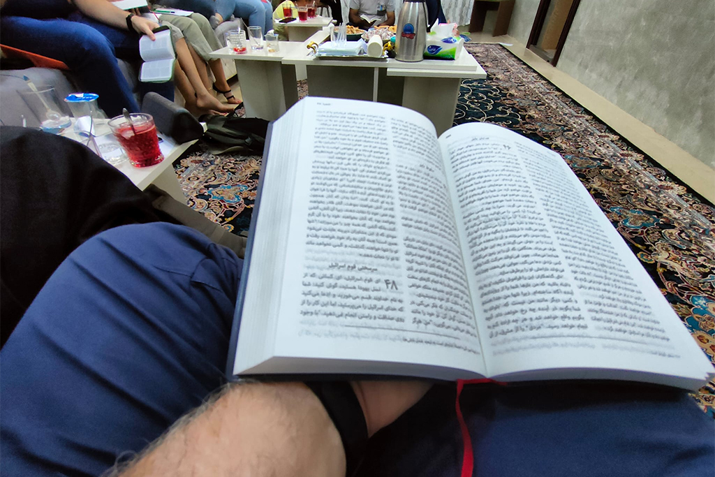 Man holding in his lap a Bible written in Arabic