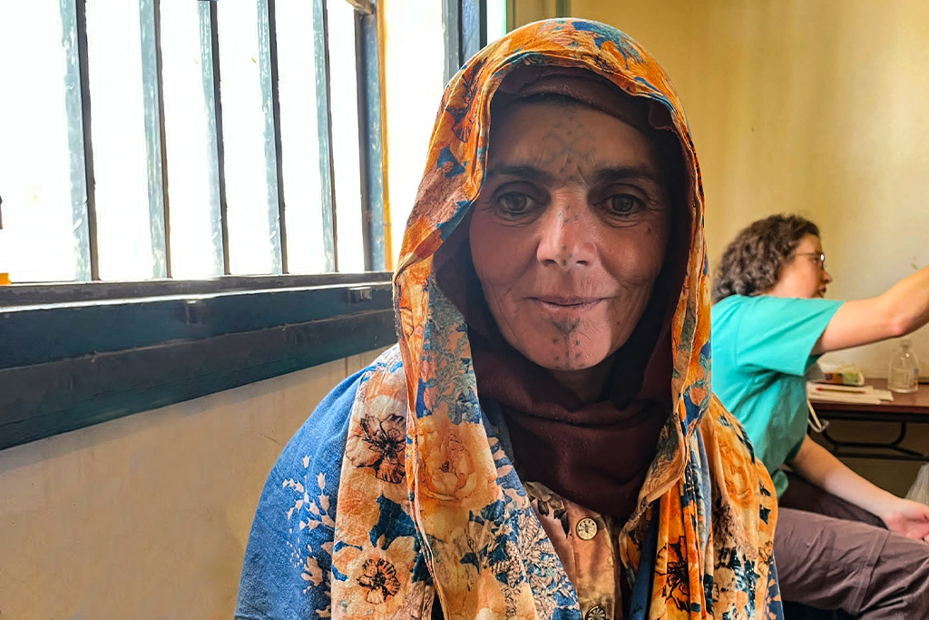 Muslim refugee woman with markings on her face and a head covering sitting in a building in Europe
