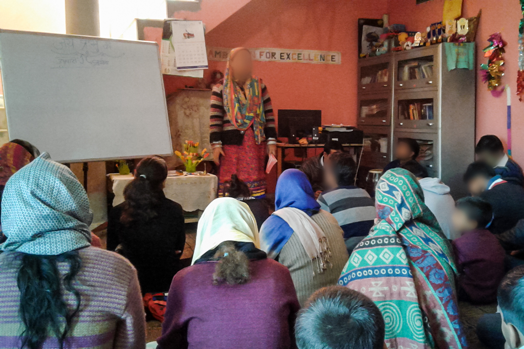 South Asian Christians sitting on the floor in a member's house for church