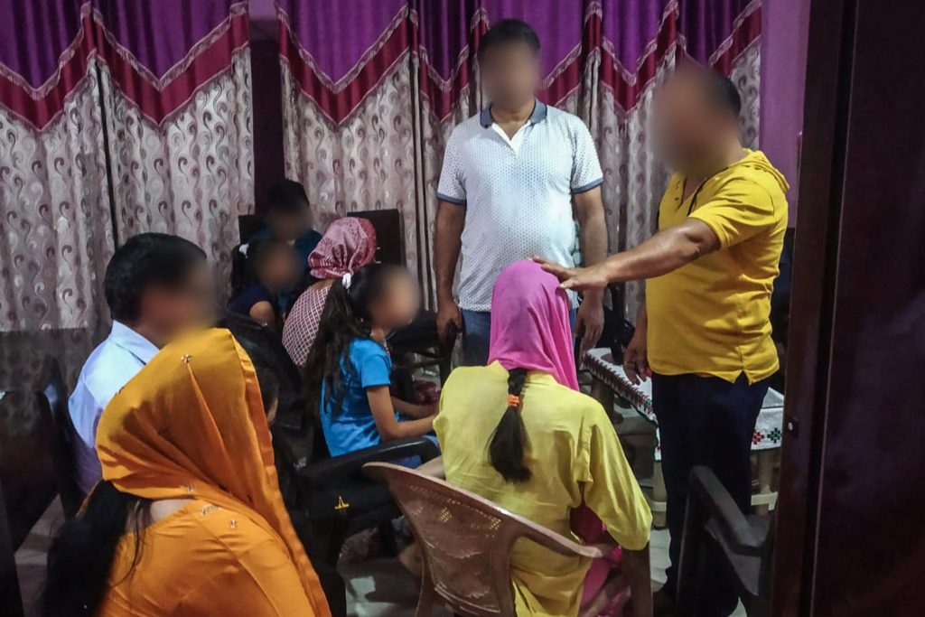 Southeast Asian Christian man with his hand on top of a girls head praying for her while others sit nearby