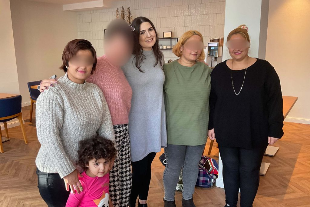 Christian woman in Greece standing in a coffee shop with several refugees from foreign countries