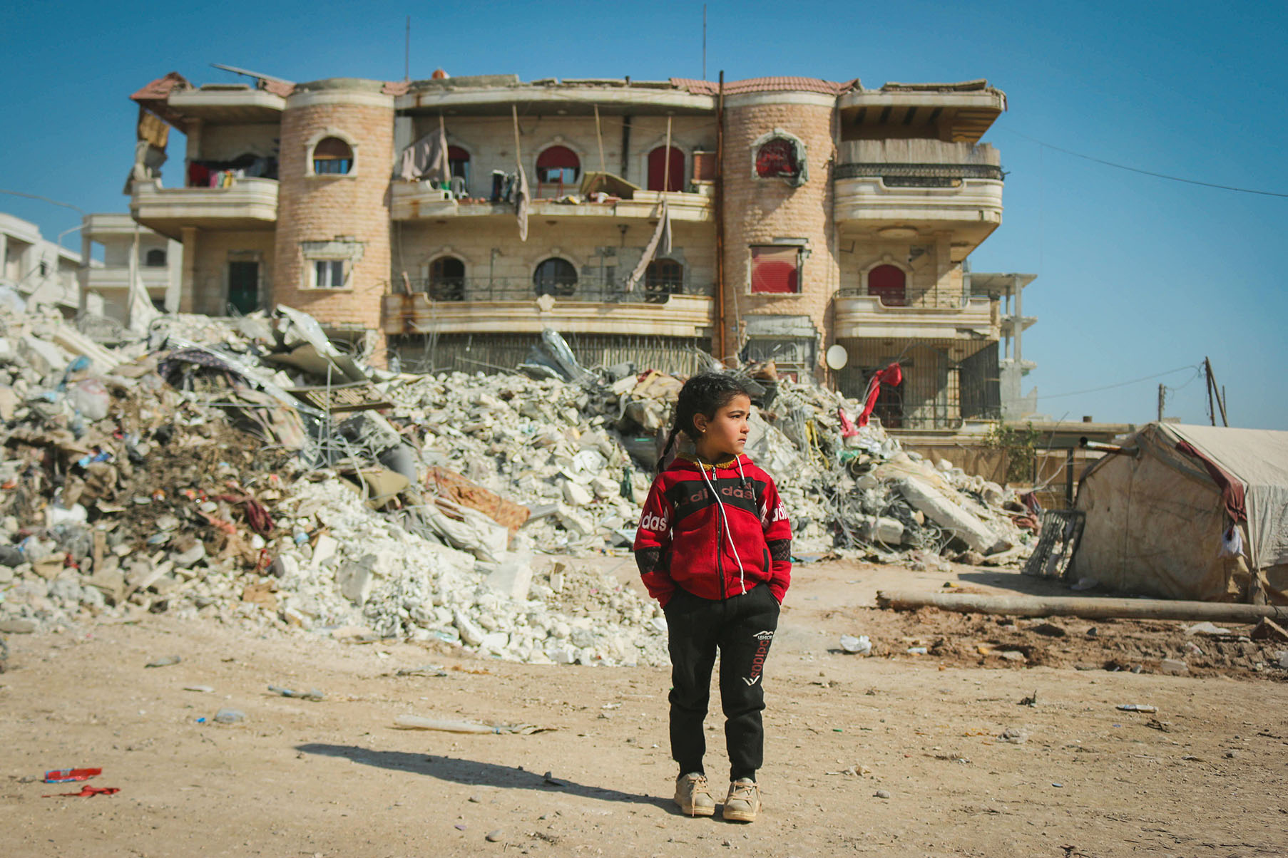 Young Moroccan girl stands in front of the rubble caused by a devastating earthquake in Morocco
