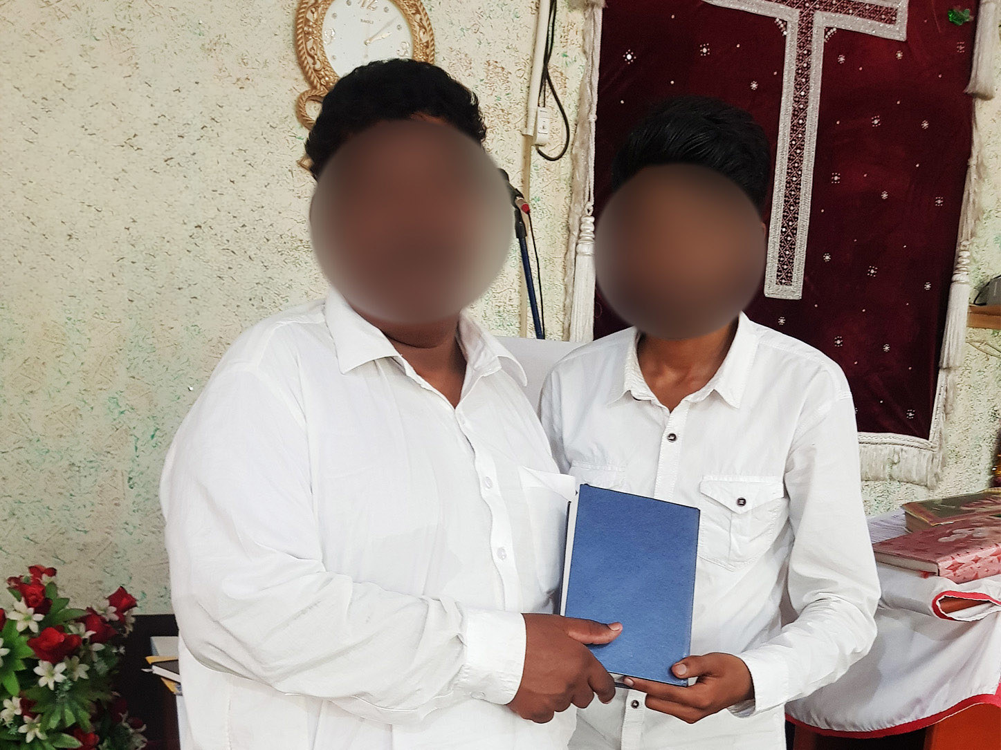Two Pakistani Christians wearing white shirts holding their new Bible