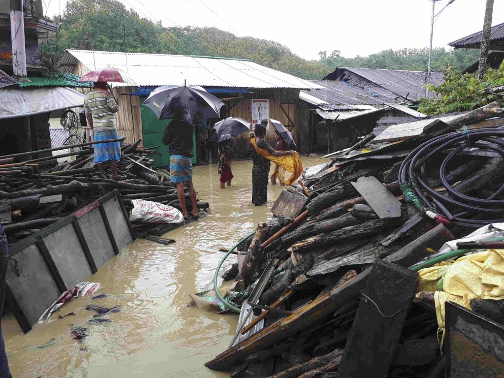 People standing among the wreckage of a village caused by torrential rains in South Asia