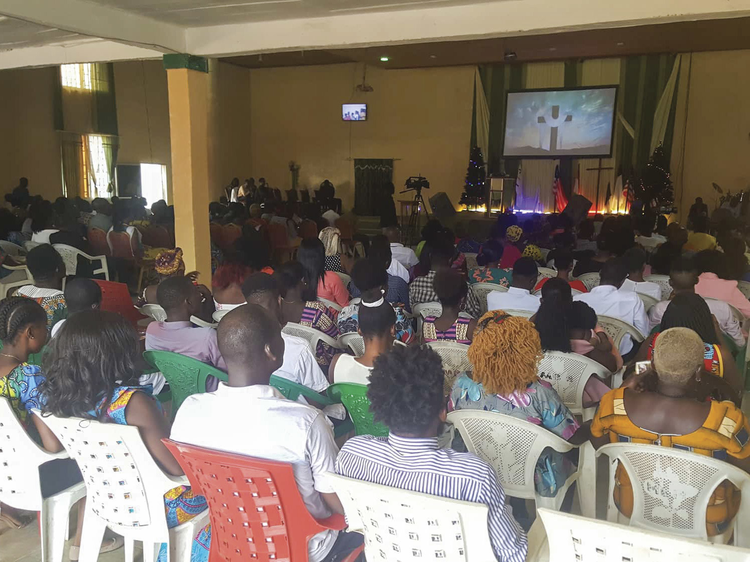 Christians in Gambia gathered together in a large church facing toward a projector screen