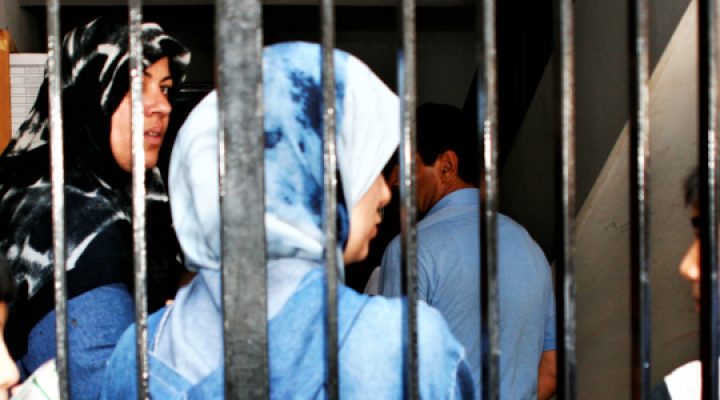 Lebanese women, boys, and man stand behind gate in concrete building